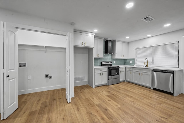 kitchen featuring white cabinets, wall chimney exhaust hood, decorative backsplash, and stainless steel appliances