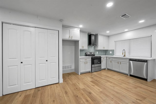 kitchen with backsplash, sink, light hardwood / wood-style flooring, wall chimney exhaust hood, and stainless steel appliances