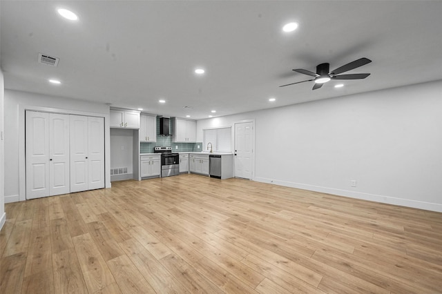 unfurnished living room featuring light hardwood / wood-style floors, ceiling fan, and sink