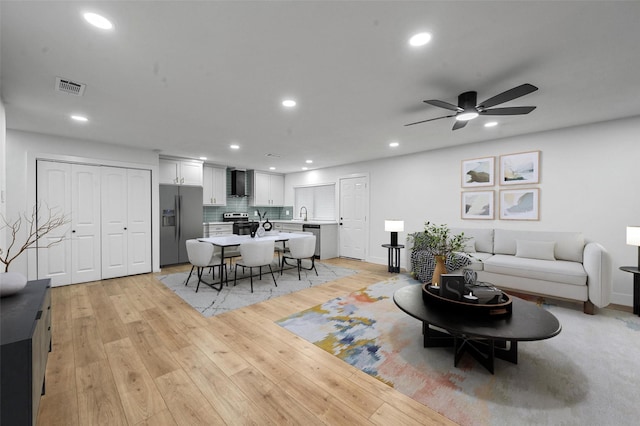 living room with light hardwood / wood-style flooring and ceiling fan