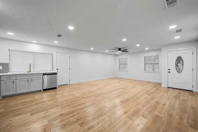 unfurnished living room with ceiling fan, sink, and light wood-type flooring