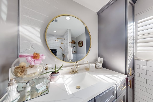 bathroom with visible vents, vanity, and walk in shower