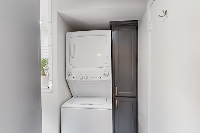 laundry area featuring cabinets and stacked washing maching and dryer