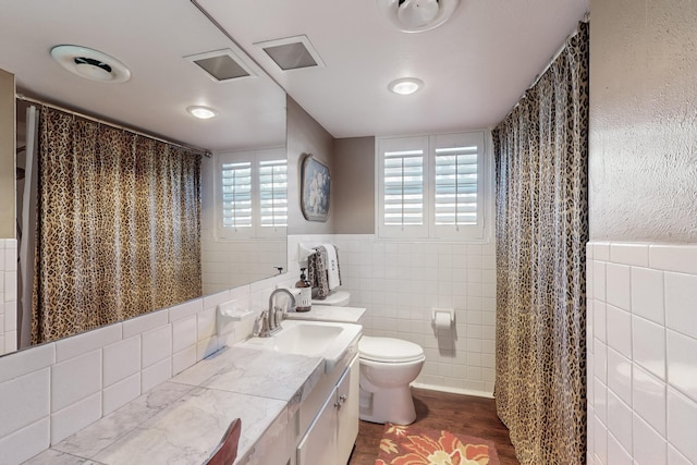 bathroom with vanity, wood-type flooring, tile walls, and toilet