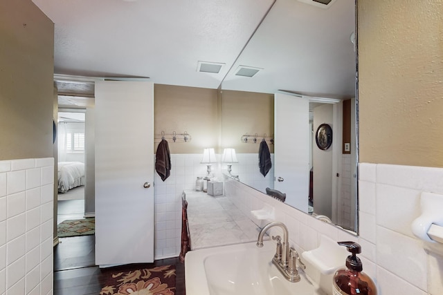 bathroom featuring hardwood / wood-style flooring, tile walls, and sink