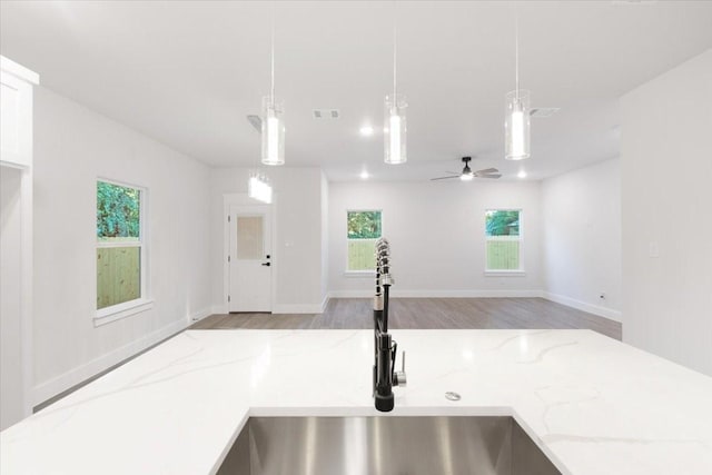 kitchen featuring light stone countertops, sink, hanging light fixtures, and ceiling fan