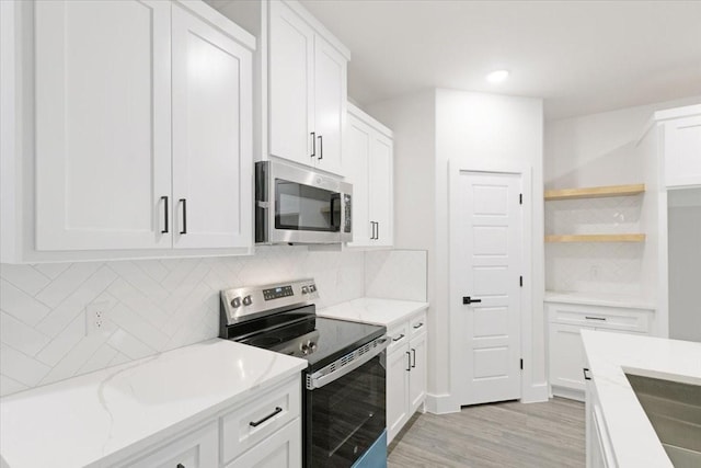 kitchen featuring decorative backsplash, light stone countertops, appliances with stainless steel finishes, light hardwood / wood-style floors, and white cabinetry