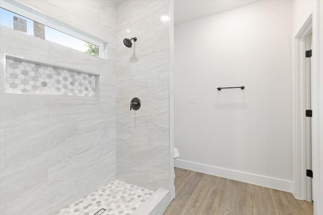 bathroom featuring tiled shower, hardwood / wood-style floors, and toilet