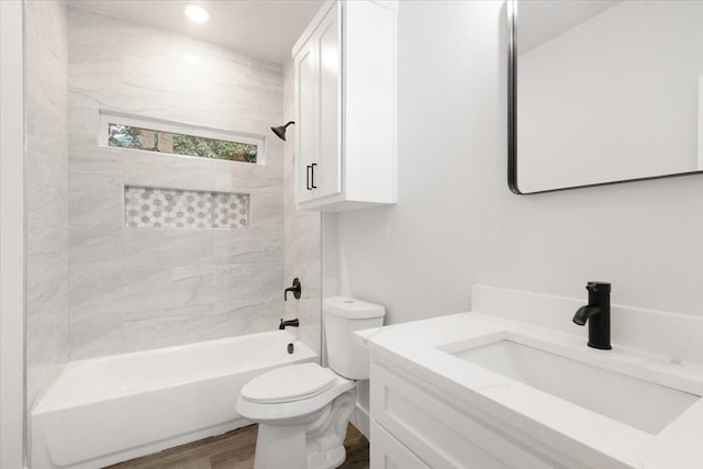 full bathroom with hardwood / wood-style floors, tiled shower / bath combo, toilet, and vanity