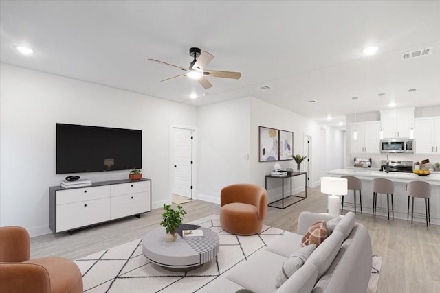 living room with ceiling fan and light hardwood / wood-style flooring