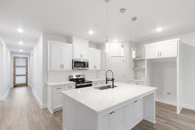 kitchen featuring white cabinetry, sink, hanging light fixtures, a kitchen island with sink, and appliances with stainless steel finishes