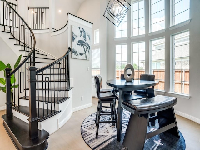 dining space featuring a chandelier, light hardwood / wood-style floors, and a high ceiling