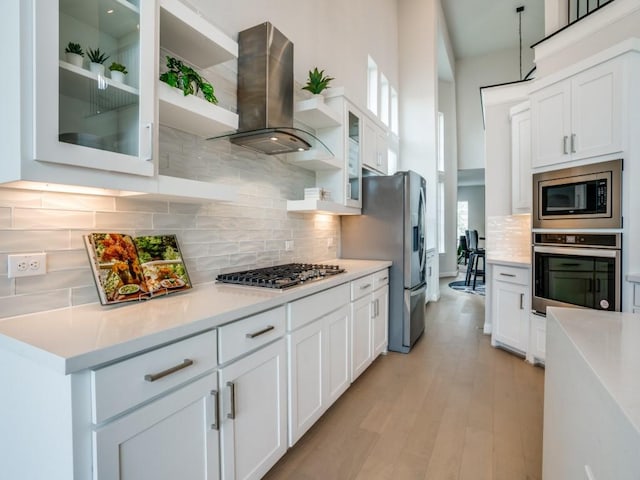 kitchen featuring appliances with stainless steel finishes, island range hood, and white cabinets