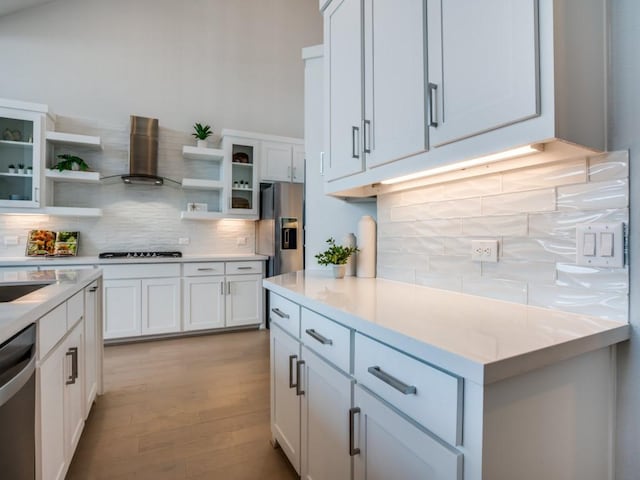 kitchen with white cabinetry, appliances with stainless steel finishes, backsplash, and wall chimney range hood