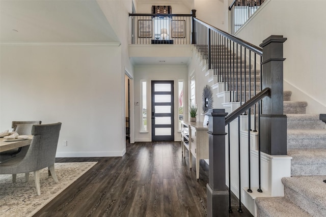 foyer entrance with dark hardwood / wood-style floors, crown molding, and a high ceiling