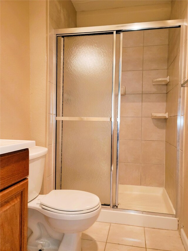 bathroom featuring tile patterned flooring, vanity, toilet, and walk in shower