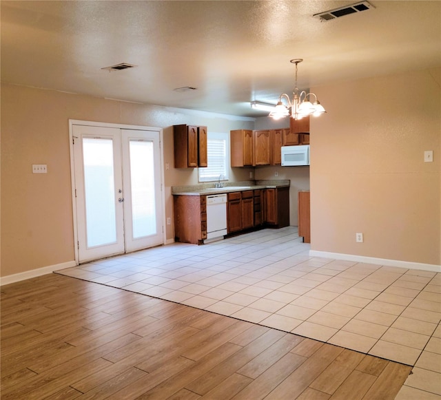 kitchen featuring french doors, white appliances, sink, decorative light fixtures, and light hardwood / wood-style floors