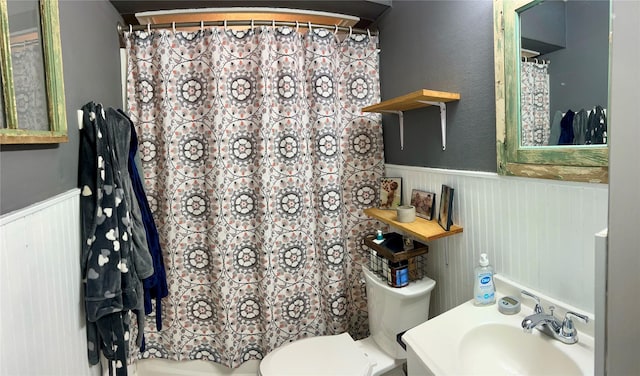 bathroom featuring curtained shower, sink, wood walls, and toilet