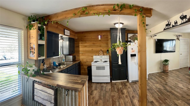 kitchen with wood walls, white appliances, dark wood-type flooring, sink, and butcher block counters