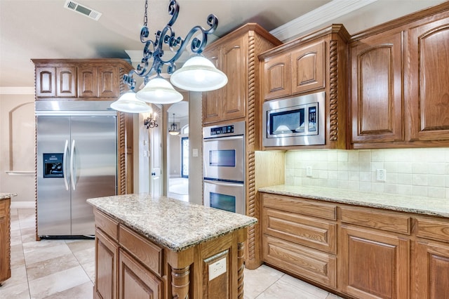 kitchen with crown molding, built in appliances, hanging light fixtures, light stone countertops, and backsplash