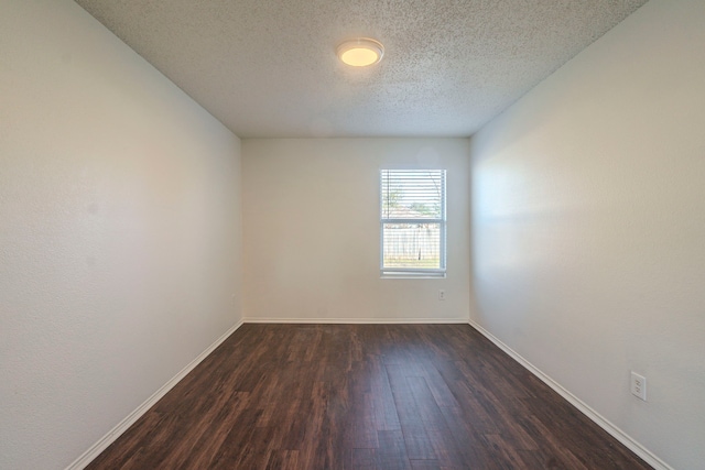 empty room with dark wood-type flooring and a textured ceiling