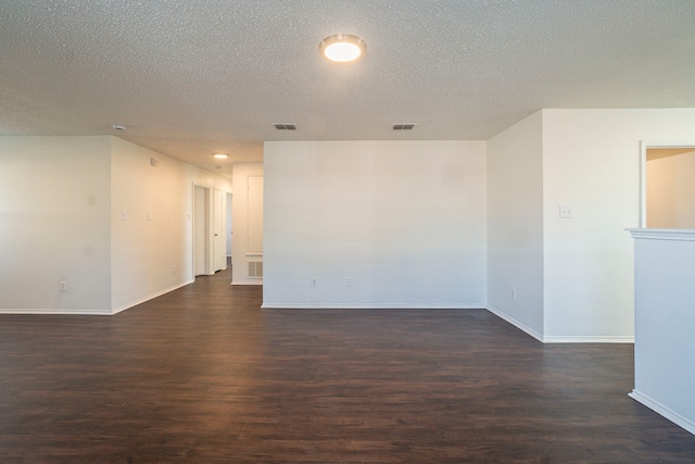 spare room featuring dark wood-type flooring and a textured ceiling