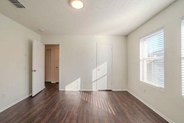 spare room with dark hardwood / wood-style floors and a textured ceiling