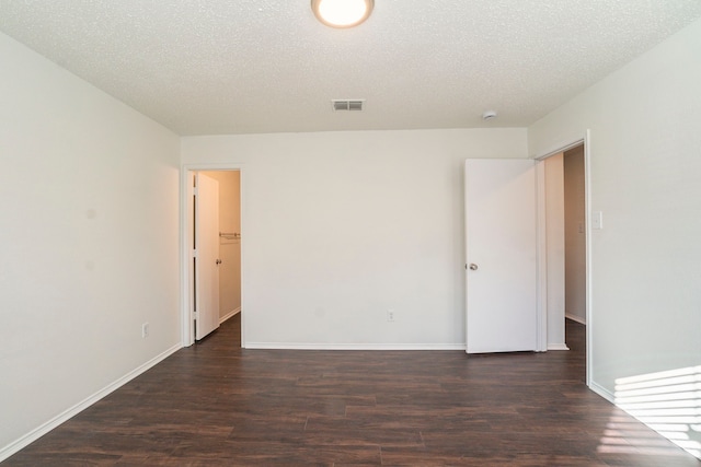 spare room with dark wood-type flooring and a textured ceiling