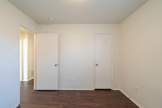 unfurnished bedroom with dark wood-type flooring and a textured ceiling