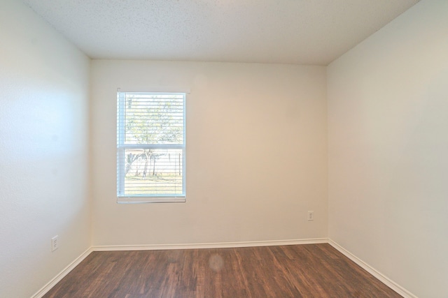 unfurnished room with dark wood-type flooring and a textured ceiling