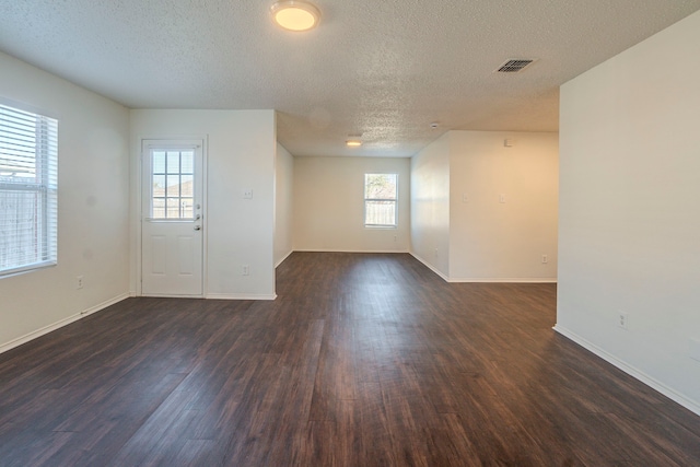 unfurnished room featuring a textured ceiling and dark hardwood / wood-style flooring