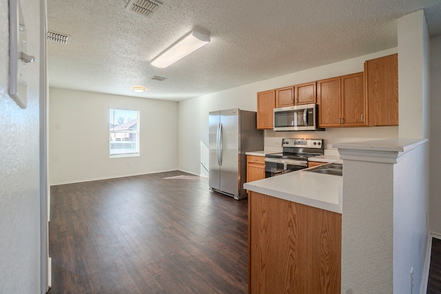 kitchen featuring appliances with stainless steel finishes, dark hardwood / wood-style floors, and a textured ceiling