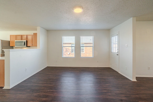 unfurnished living room with dark wood-type flooring and a textured ceiling