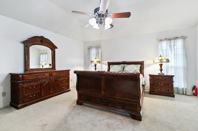 bedroom with ceiling fan, multiple windows, light colored carpet, and lofted ceiling