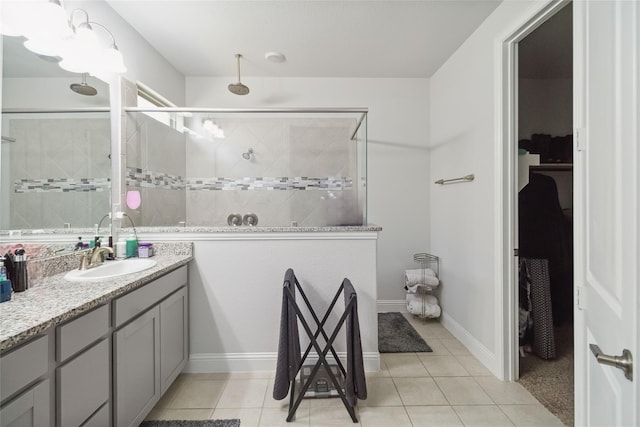 bathroom featuring tiled shower, vanity, and tile patterned flooring