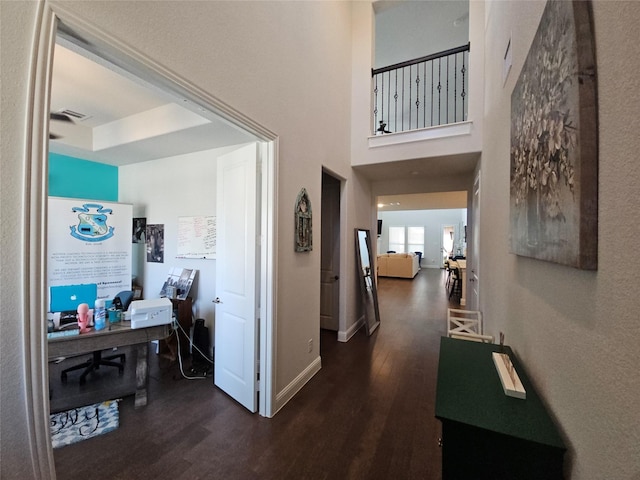 hallway featuring dark hardwood / wood-style floors and a tray ceiling