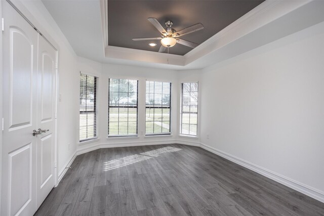 unfurnished room with ceiling fan, dark hardwood / wood-style flooring, and a raised ceiling