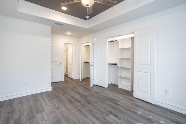 unfurnished bedroom featuring hardwood / wood-style floors, a raised ceiling, ceiling fan, and ornamental molding