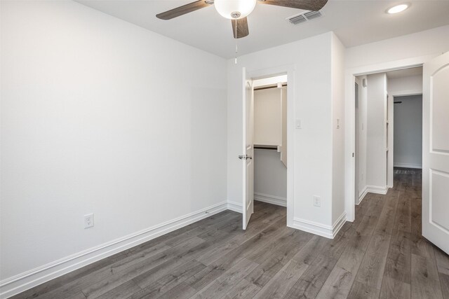 unfurnished bedroom with hardwood / wood-style flooring, ceiling fan, a walk in closet, and a closet