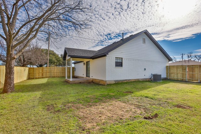 back of property with a yard and central AC unit