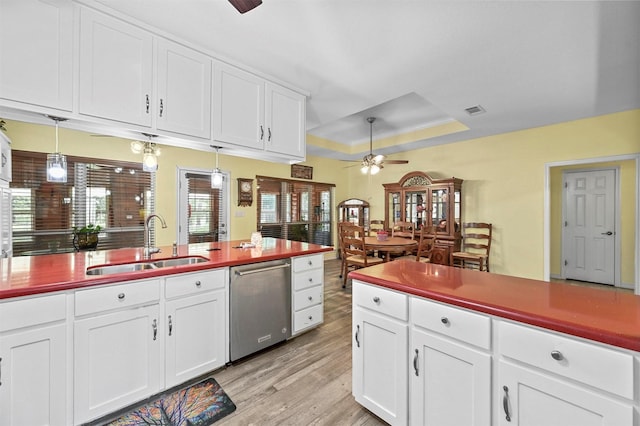 kitchen with ceiling fan, sink, a raised ceiling, stainless steel dishwasher, and light wood-type flooring