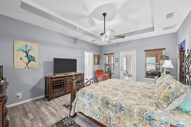 bedroom featuring light hardwood / wood-style flooring, a raised ceiling, and ceiling fan