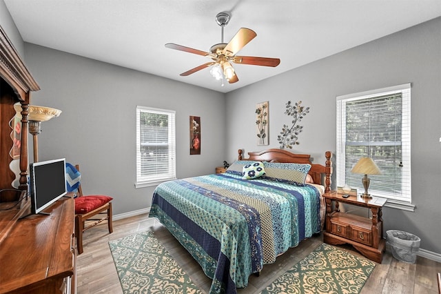 bedroom featuring multiple windows, hardwood / wood-style floors, and ceiling fan