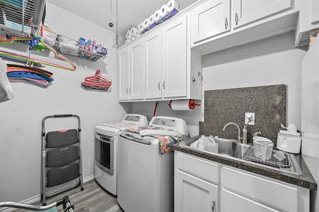 laundry room featuring washer and dryer, light hardwood / wood-style flooring, cabinets, and sink