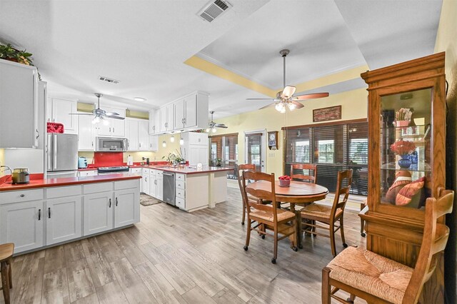 dining room featuring a tray ceiling, light hardwood / wood-style flooring, and ornamental molding