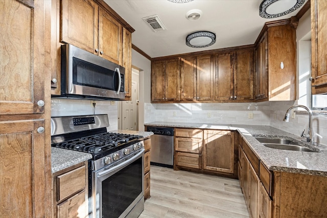 kitchen featuring backsplash, sink, light wood-type flooring, appliances with stainless steel finishes, and light stone counters