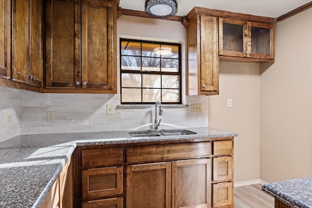 kitchen featuring backsplash, light wood-type flooring, sink, and dark stone counters