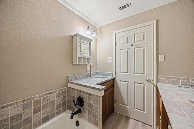 bathroom with a bathing tub, vanity, wood-type flooring, and ornamental molding