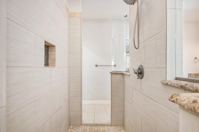 bathroom featuring tile patterned flooring and a tile shower