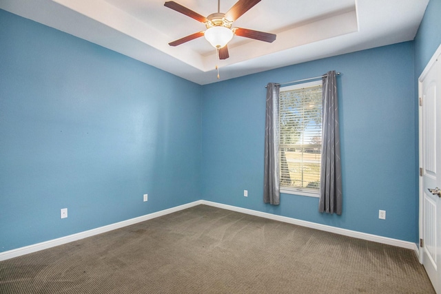 carpeted empty room featuring a raised ceiling and ceiling fan